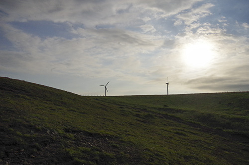 遠くに見える風力発電の風車の写真